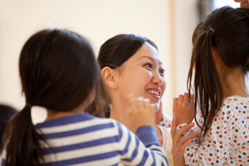 笑顔の保育士と保育園児のうしろ姿