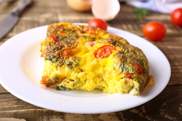Omelet with vegetables close-up on wooden background