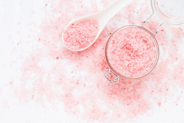 Pink bath salt in a glass jar on pink bath salt background. Spa concept. Selective focus