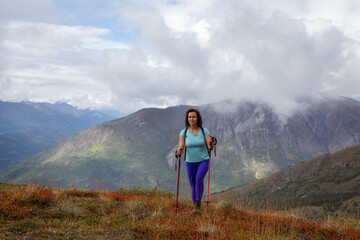 Adventurous Girl Hiking up the Nares Mountain during a cloudy and sunny evening. Taken at Carcross, near Whitehorse, Yukon, Canada.