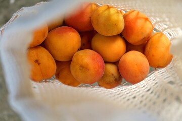 Reusable mesh bag filled with apricots. Top view, selective focus.