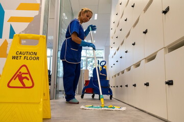 
A cleaning leady cleans the floor in an office with mop