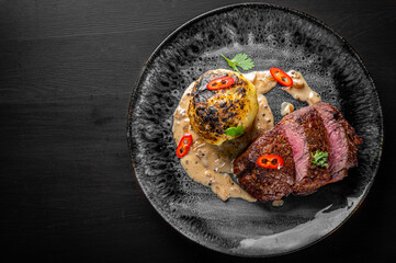 Grilled beef steak filet mignon with potato and sauce in plate on wooden table
