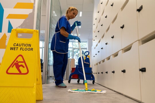 
A cleaning leady cleans the floor in an office with mop