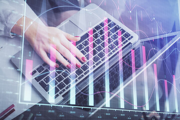 Double exposure of businesswoman hands typing on computer and financial graph hologram drawing. Stock market analysis concept.
