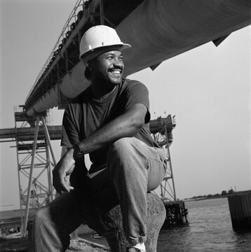 African American male welder next to water