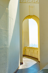 Outside corridor on Greek design building with arch/ arched walls and city view in background.