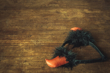 Red horns for a holiday, a rim on the head for a holiday, on a wooden table.