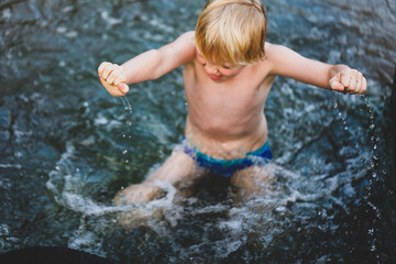 Fototapeta premium Boy swimming in river with hands and water droplets in focus. Summer in central New South Wales, Australia