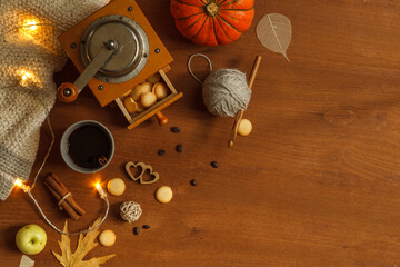 Autumn flatlay with a vintage wooden coffee grinder, a knitted blanket, a Cup of coffee, hearts and a garland. Top view on a dark background