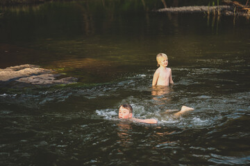 Two brothers swimming in river with strong current. Splashing around in water.