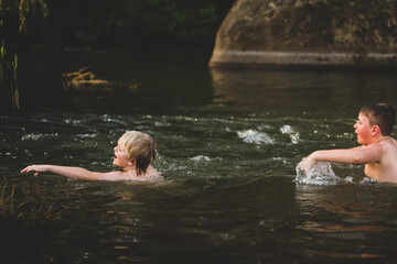 Two brothers swimming in river with strong current. Splashing around in water.