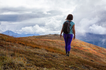 Adventurous Girl Hiking up the Nares Mountain during a cloudy and sunny evening. Taken at Carcross, near Whitehorse, Yukon, Canada.