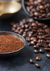 Fresh raw organic coffee beans with powder on dark background.