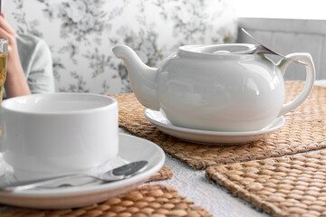 A teapot and a cup with tea on a table in a restaurant, hot warming drinks and autumn cosiness, comfort