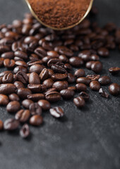 Fresh raw organic coffee powder and beans in vintage steel scoop on black.