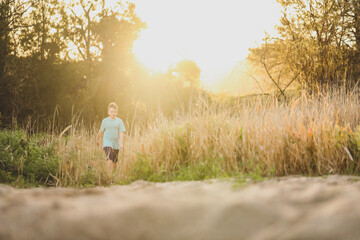 Boy walking in long grass at dusk