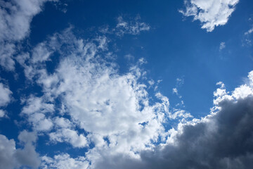white clouds against the blue sky. bright sun behind clouds bottom view. natural background sky on summer day