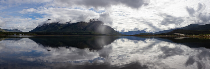 Panoramic View of Nares Lake with Mountains in the Background during a cloudy morning sunrise. Taken in Carcross, Yukon, Canada.