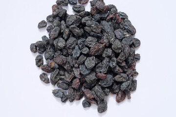 Black raisins on a white background. Dry blue large raisins top view. A pile of dried raisins.