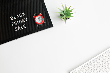 White text Black Friday Sale on black letter board with computer keyboard and Alarm Clocks