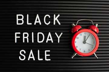 White text Black Friday Sale on black letter board and alarm clock, closeup.