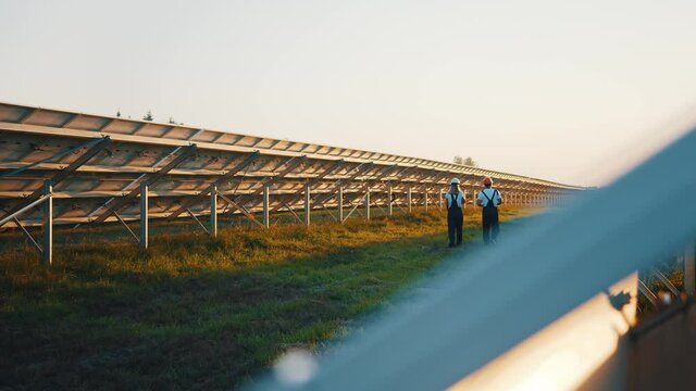 Solar Farm. Power Station. Two Cooperative Workers Inspecting Photovoltaic Ecological Industrial Field Outdoor. Rows Of Solar Batteries. Alternative Energy.