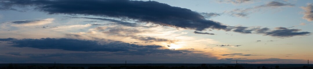 Storm clouds against a blue sky. The sun is hidden. Panorama. Tragic gloomy sky. Fantastic skies on the planet earth. Twilight, nightfall.