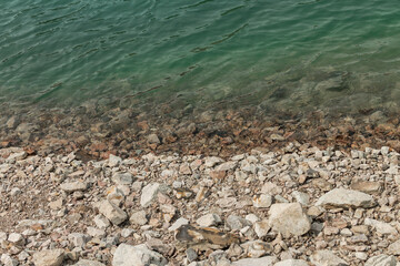 Beautiful textures of rocks and turquoise water in the lake. Top view outdoors on sunny summer day.