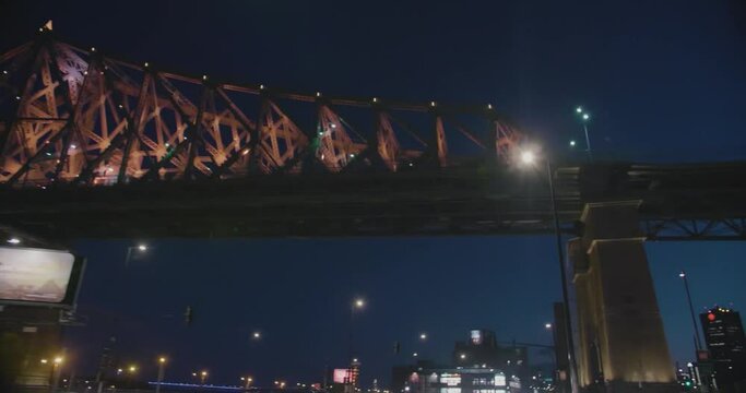 Montreal, Canada - April 15th 2017 : Worm eye shot of Jacques Cartier Bridge, buildings and street lights at night filmed while car driving under the bridge.