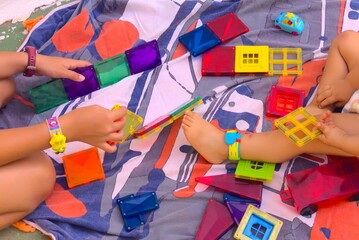 Málaga, Spain. Children playing a colorful plastic magnet construction game on a piece of fabric on the floor.