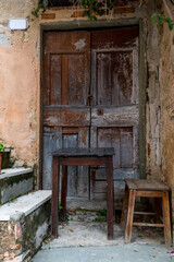 Old wooden door in a Tuscan village with two stools and doorsteps