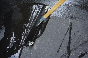 Man sealing asphalt driveway/Sealcoating
