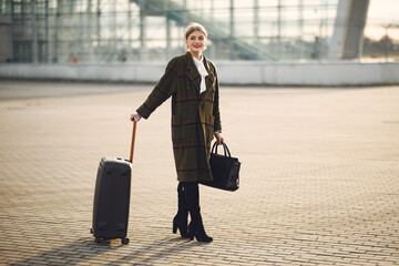 Woman by the airport. Girl with suitcase. Lady in a brown coat.