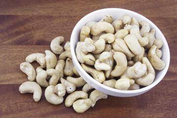 Cashew nuts in white bowl on wooden table