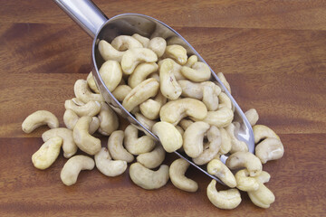 Cashew nuts with metallic scoop on wooden table