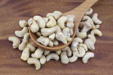 Cashew nuts with spoon on wooden table