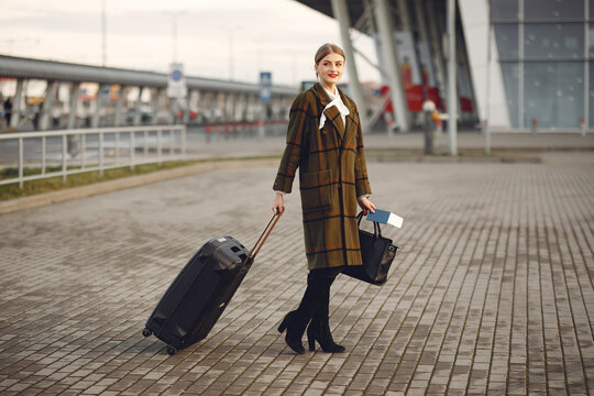 Woman by the airport. Girl with suitcase. Lady in a brown coat.