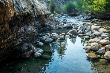 Gordijnen Bos rivier natural hot spring waterfall streaming down over rocks into pool of warm water with steam  © mariekazalia