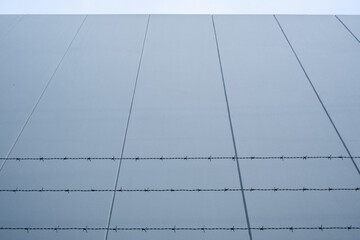 Looking up at barbed wire against concrete wall with copy space