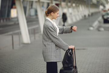 Woman by the airport. Girl with suitcase. Lady in a gray jacket.