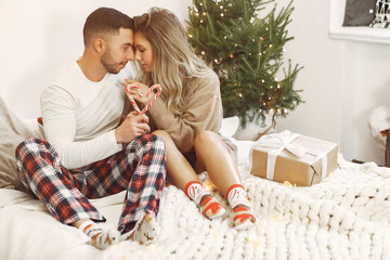 Couple sitting on a bed. Lady in a brown sweater. Woman with candy.