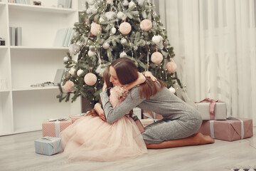 Naklejka premium Mother in a green sweater. Family near christmas tree. Little girl in a cute dress