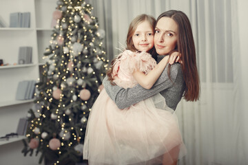 Mother in a green sweater. Family near christmas tree. Little girl in a cute dress