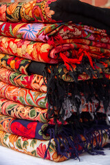 Kashmiri embroidered wool shawls folded in a stack. 