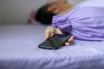 A black smartphone in man hand on purple bed