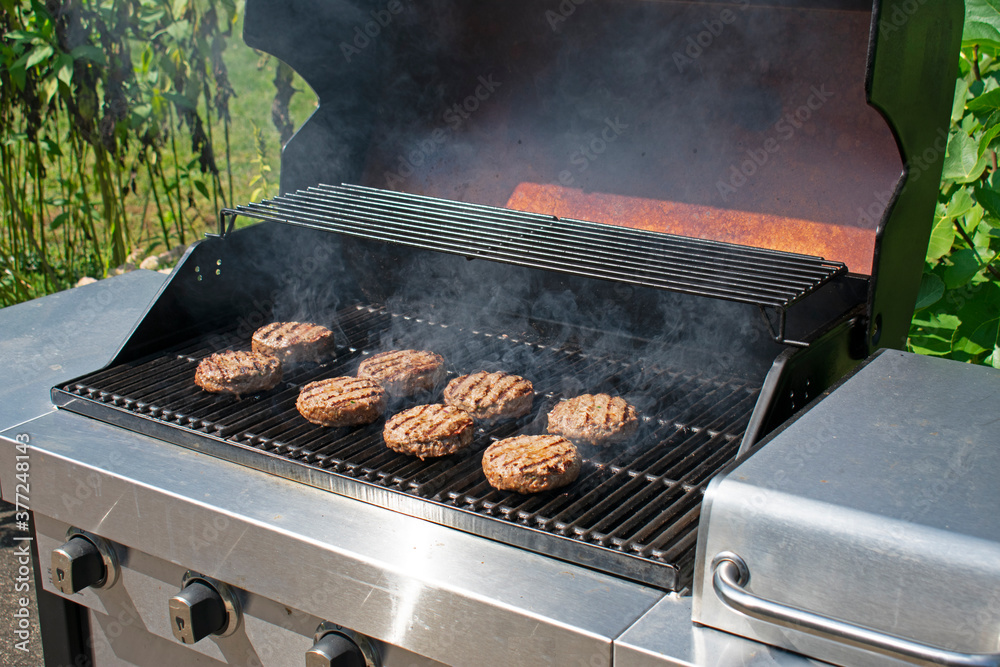 Wall mural Grilling delicious meats in a smoke filled barbecue grill on a beautiful summer day -12