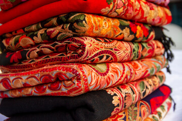 Kashmiri embroidered wool shawls folded in a stack. 