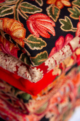 Kashmiri embroidered wool shawls folded in a stack. 