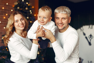 Mother in a white sweater. Family with christmas gifts. Child with parents in a christmas decorations.